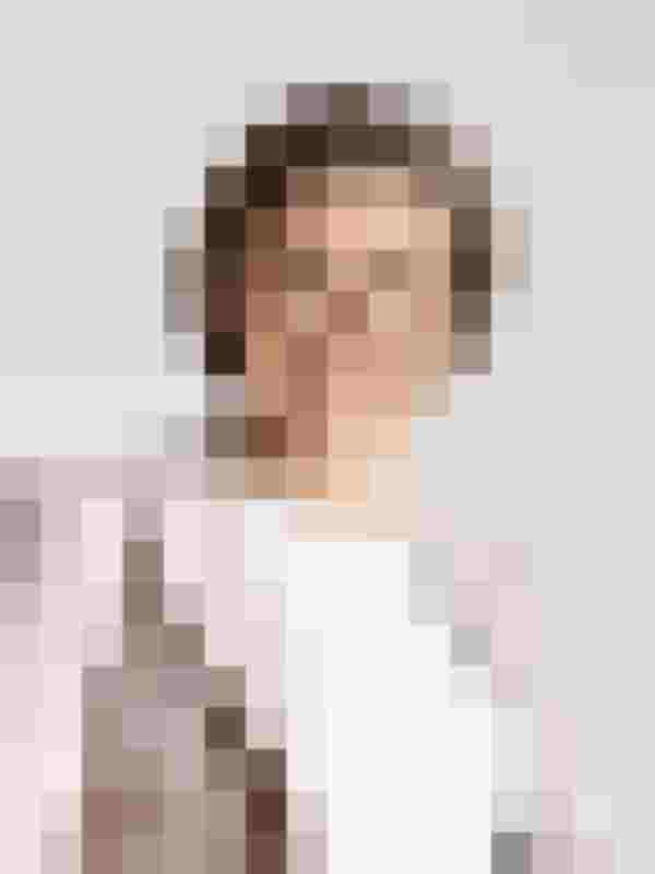 Porträt einer lächelnden Frau mit Brille und Perlenkette