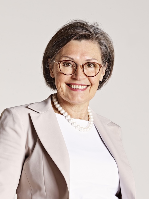 Porträt einer lächelnden Frau mit Brille und Perlenkette